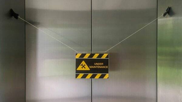 elevator with black & yellow caution sign that reads "under maintenance"